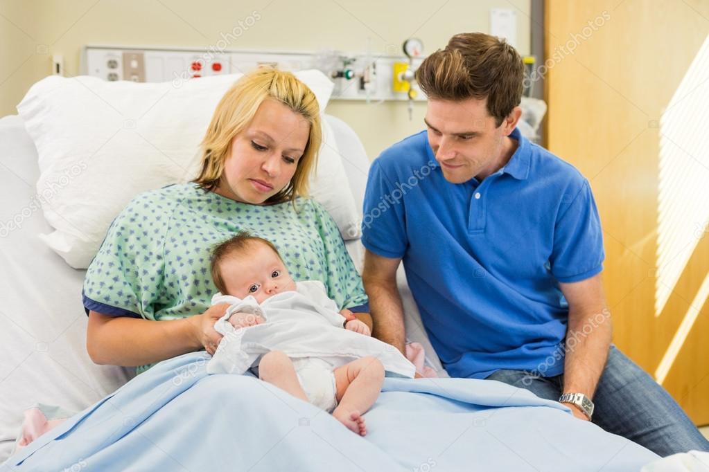 Couple Looking At Newborn Baby In Hospital Room