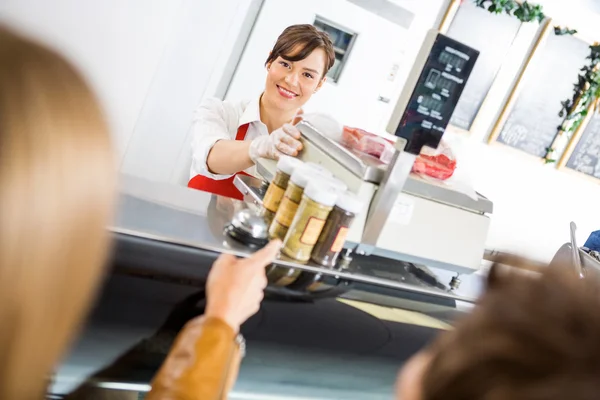 Försäljare på counter behandlande kunder i charkuteri — Stockfoto