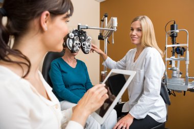 Eyecare Specialist Examining Senior Woman clipart