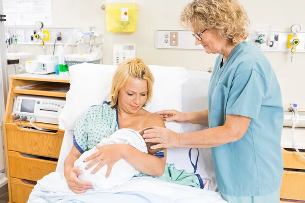 Enfermera ayudando a la mujer en la lactancia materna bebé en el hospital — Foto de Stock