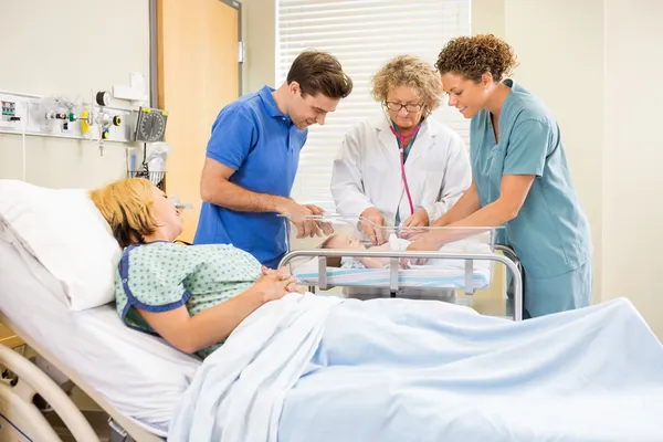 Medico esaminando bambino mentre genitori e infermiera guardando il suo — Foto Stock