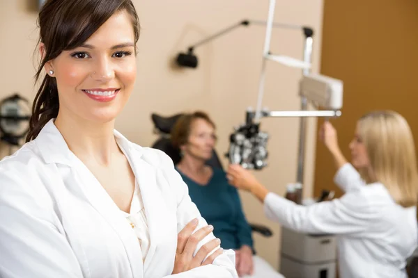 Женщина-оптометрист с коллегой по обследованию пациента — стоковое фото