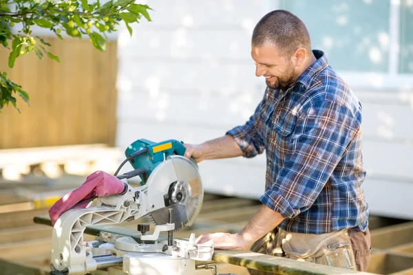 Carpintero cortando madera usando sierra de mesa en el sitio de construcción —  Fotos de Stock