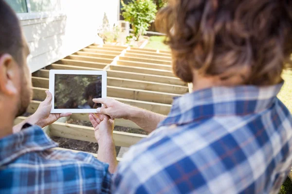 Carpenter Pointing At Digital Tablet While Coworker Holding It — Stock Photo, Image