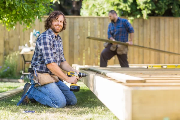 Fiducioso lavoratore perforazione del legno in cantiere — Foto Stock