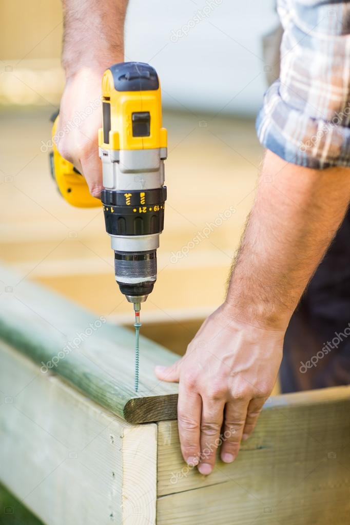 Carpenter's Hands Using Drill On Wood
