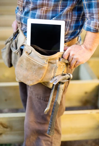 Brzuch cieśla z komputera typu tablet i młotkiem w arzędzi — Zdjęcie stockowe