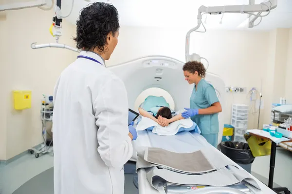 Medico guardando infermiera preparazione paziente per CT scansione — Foto Stock