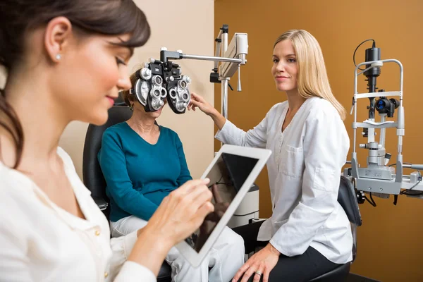 Médicos de Ojos examinando a una mujer mayor en la tienda —  Fotos de Stock