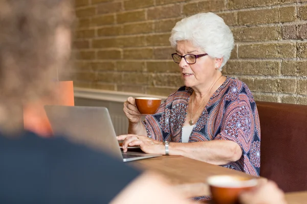 Cliente usando laptop enquanto toma café no café — Fotografia de Stock