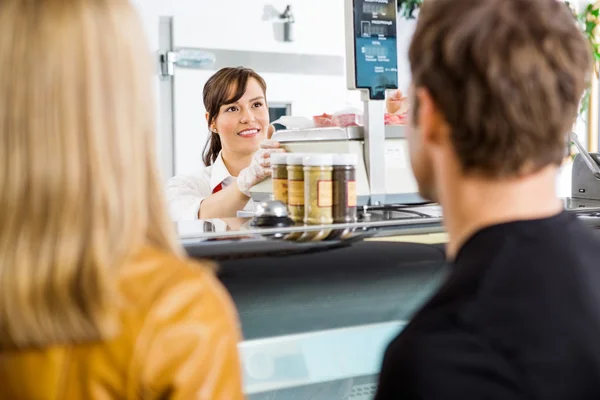 Verkoopster kijken naar klanten in slagerij — Stockfoto