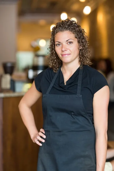 Camarera de pie con la mano en la cadera en el café — Foto de Stock