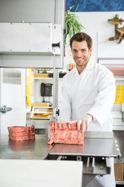 Retrato de carnicero rebanando carne en sierra de banda —  Fotos de Stock