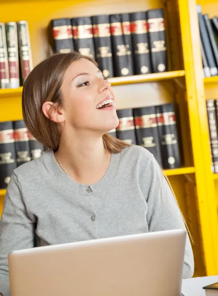 Student med laptop tittar bort i Universitetsbiblioteket — Stockfoto