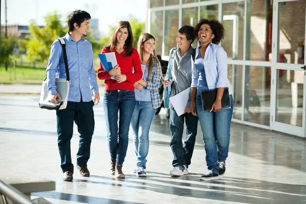 Vrolijke studenten wandelen op de campus — Stockfoto