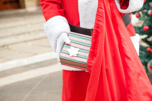 Старшеклассник, одетый как Санта Клаус, кладет подарок в сумку — стоковое фото