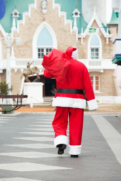 Papai Noel levando saco enquanto caminhava no pátio — Fotografia de Stock