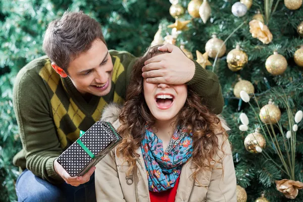 Hombre sorprendente mujer con regalo en la tienda de Navidad — Foto de Stock