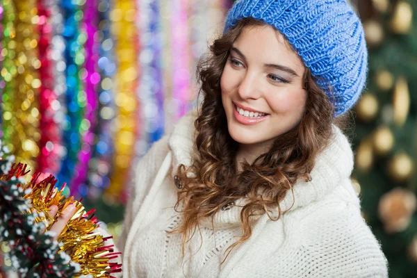 Jonge vrouw kiezen tinsels op te slaan — Stockfoto