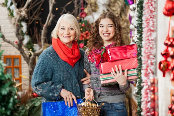 Feliz madre e hija con regalos de Navidad en la tienda —  Fotos de Stock