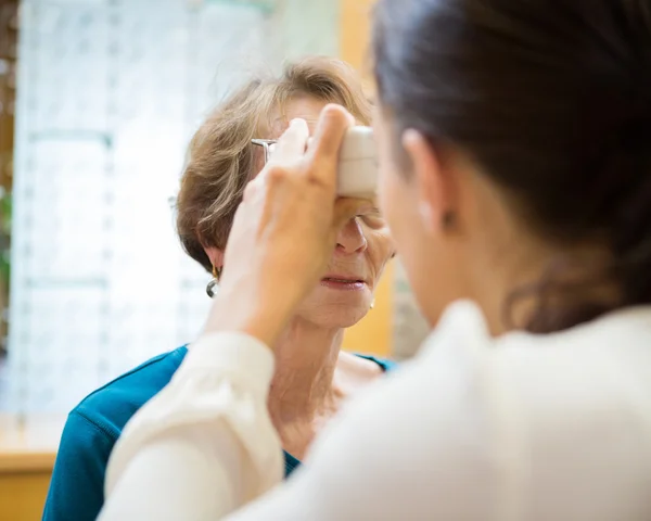 Optométriste examinant la vision de la femme âgée — Photo