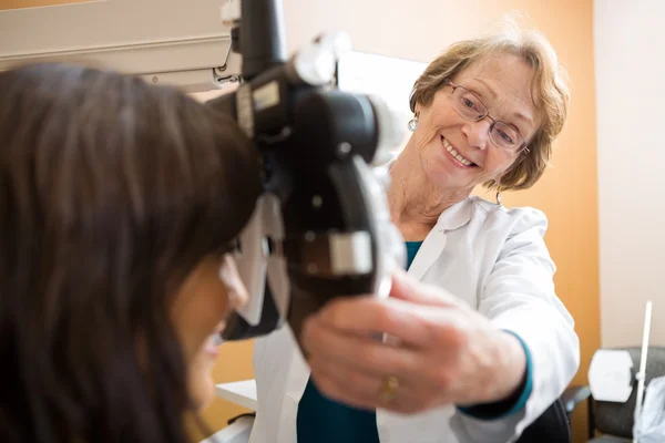 Optometrista feliz ajustando Phoropter para paciente — Fotografia de Stock