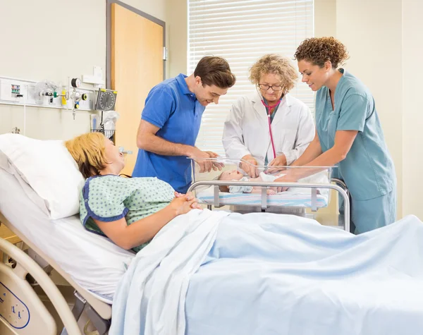 Médico examinando a la niña mientras los padres y la enfermera la miran — Foto de Stock