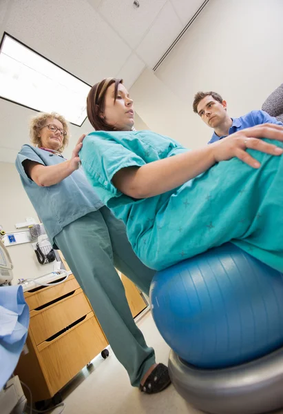 Sjuksköterska medhjälpande gravid kvinna sitter på övning boll — Stockfoto