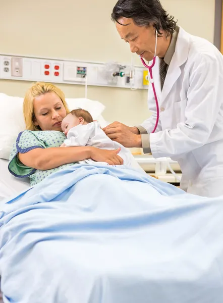 Arzt untersucht Baby, das in den Armen der Mutter schläft — Stockfoto
