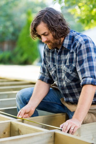 Carpenter Measuring Wood With Tape At Construction Site — Stock Photo, Image