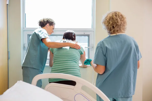 Enfermeira transportando vestido de hospital para a mulher grávida preocupada — Fotografia de Stock