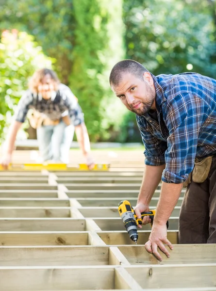 Tischler hält Bohrer auf Baustelle — Stockfoto