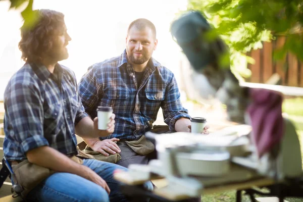 Timmerman met collega wegwerp koffiekopje houden op site — Stockfoto