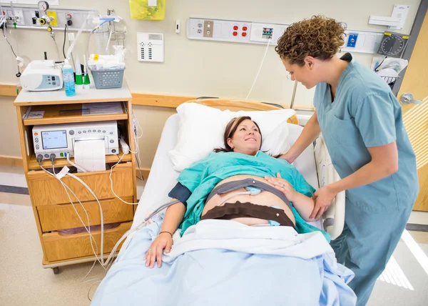 Медсестра общается с беременным пациентом, лежащим на больничной койке — стоковое фото