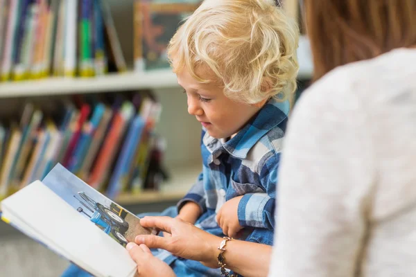 Pojke med lärare tittar på bok i biblioteket — Stockfoto