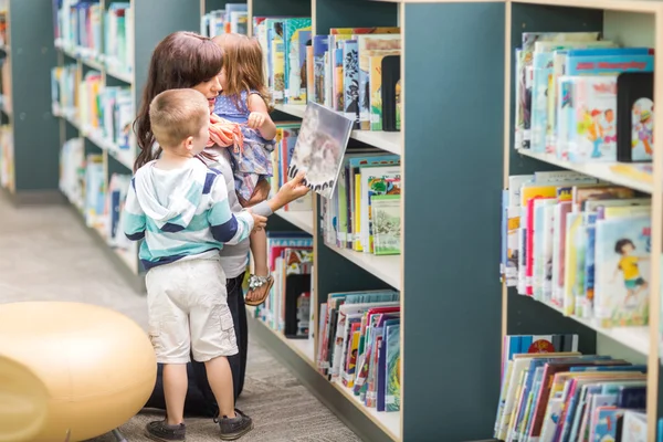 Lehrerin mit Kindern sucht Buch in Bibliothek aus — Stockfoto