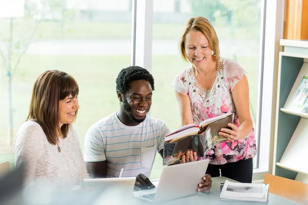 Gelukkig bibliothecaris helpen studenten in bibliotheek — Stockfoto