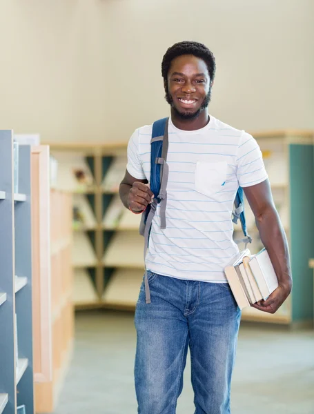 Student met rugzak en boeken in bibliotheek — Stockfoto