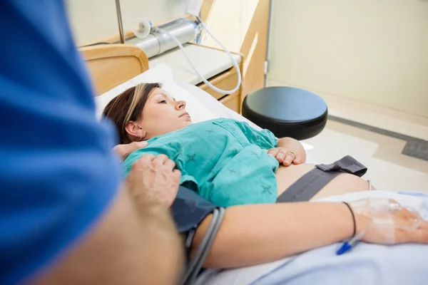 Mans hand tröstande gravida hustru liggande på sjukhussäng — Stockfoto