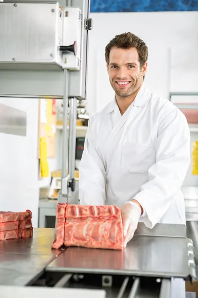 Carniceiro cortando carne em serra de fita — Fotografia de Stock