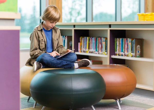 Skolpojke med digital tablet i biblioteket — Stockfoto