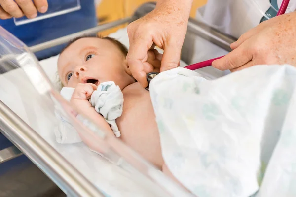 Vrouwelijke arts handen onderzoekende pasgeboren babygirl in ziekenhuis — Stockfoto