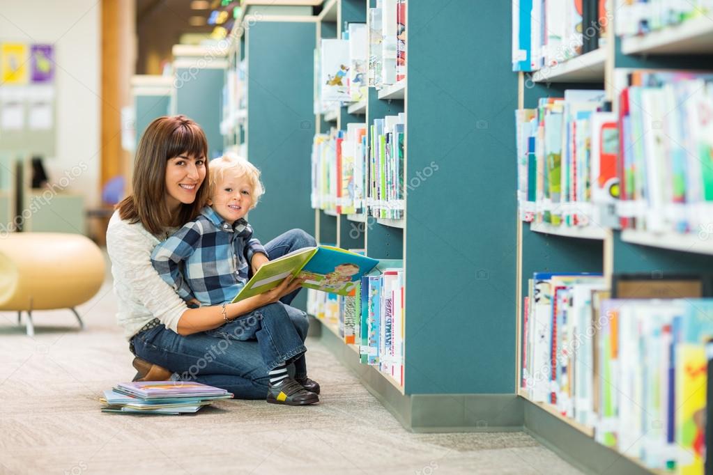 Happy Boy And Teacher Reading Book In Library