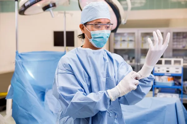 Cirurgião vestindo luvas cirúrgicas na sala de operação — Fotografia de Stock