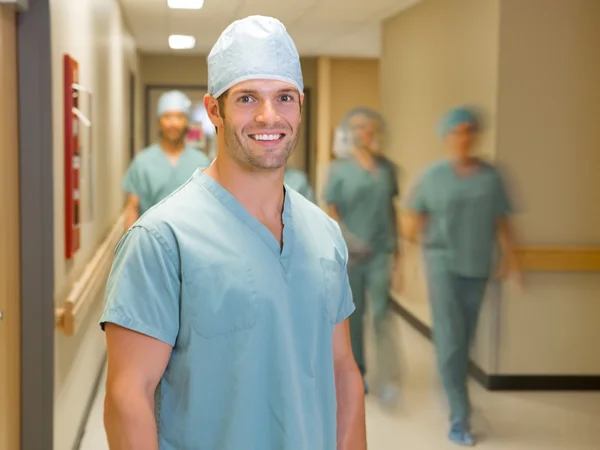 Счастливый доктор с командой в больничном коридоре — стоковое фото