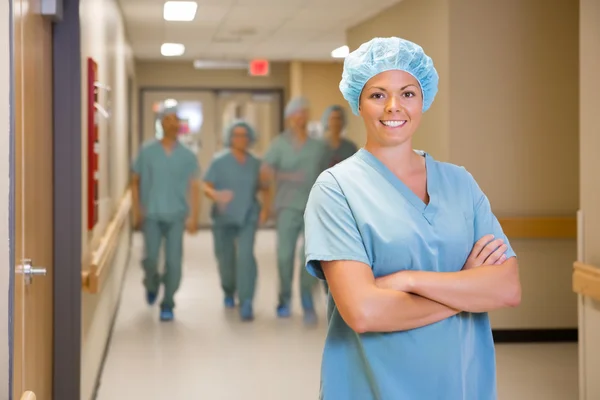 外科医生站立双手交叉在医院的走廊里 — 图库照片