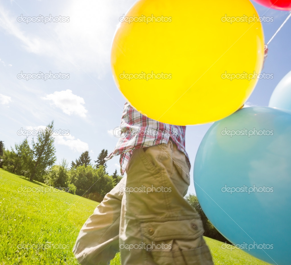 Boy With Balloons Walking In Meadow