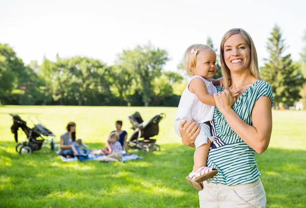 Mãe feliz carregando filha no parque — Fotografia de Stock