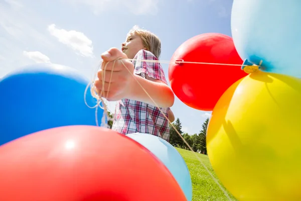 Menino com balões coloridos correndo no parque — Fotografia de Stock