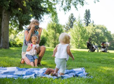Mother Photographing Daughter In Park clipart
